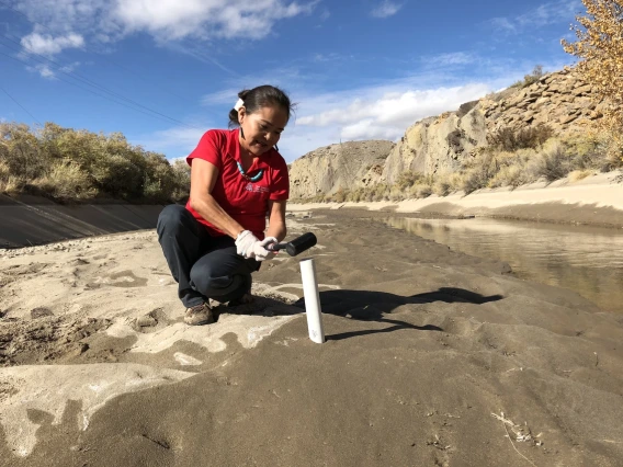 Karletta Chief using a tool to conduct hydrological fieldwork in a riverbed
